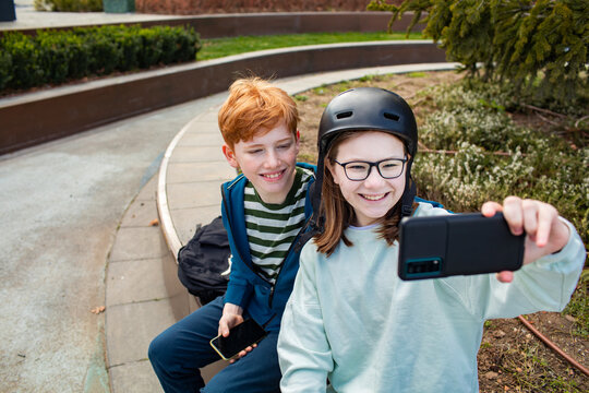 Young boy and girl taking a selfie with a smart phone in a park after skipping school