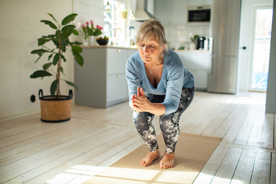 Senior caucasian woman doing yoga at home on a yoga mat