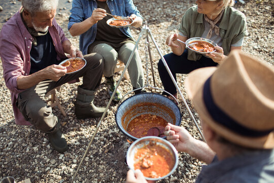 Group of senior people camping and cooking up a fish stew after a long day of hiking in the mountains and forests