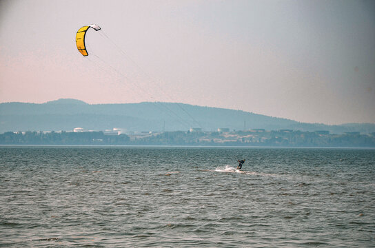 kite surfing in the water in front of an industrial plant