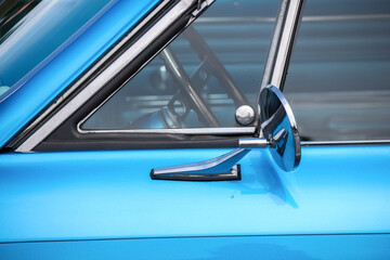 Close up view of blue classic car side view mirror.