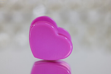 Fototapeta premium Pink Heart shaped clip close up view with reflection shallow depth of field.