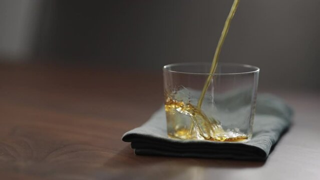 Slow motion pour nitro coffe in tumbler glass on wood table