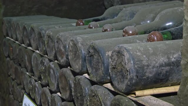 Old Aged Wine Bottles Storage in Dark Rustic Cellar Basement, Stack of Lying Dir