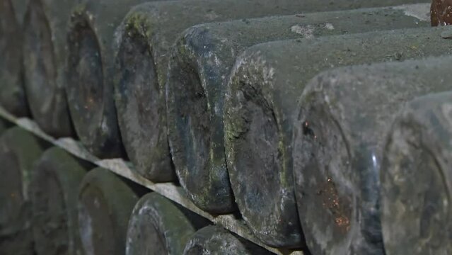 Old Aged Wine Bottles Storage in Dark Rustic Cellar Basement, Stack of Lying Dir