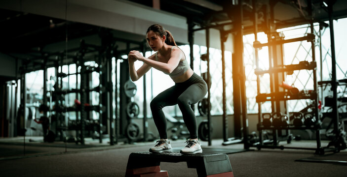 Young Sportive Woman Workout Exercising with Jumping Step Platform at Fitness Center or Gym. Fitness and Wellness Concept