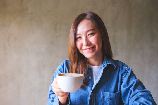 Portrait image of a beautiful young woman holding and drinking coffee