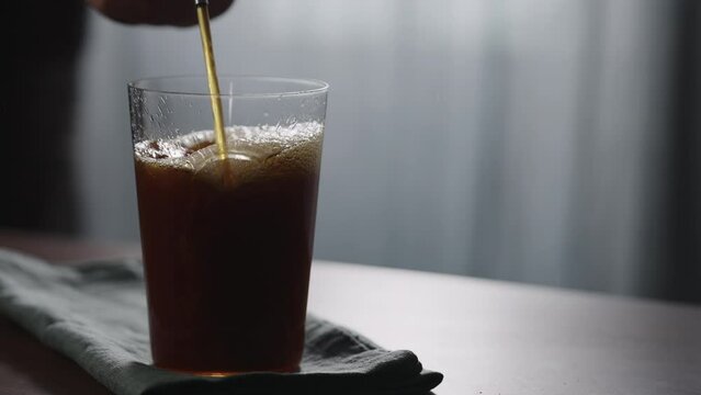 Slow motion pour nitro coffe in tumbler glass on wood table