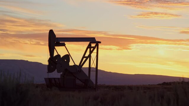 Silhouetted oil pump rig turns while operating before sunrise in Vernal, Utah