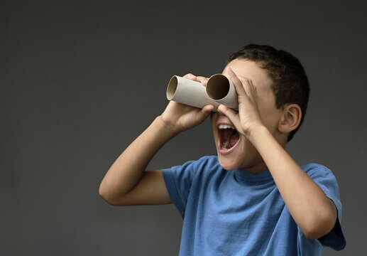 boy looking  through binoculars toilet paper roll on grey background with people stock image stock photo