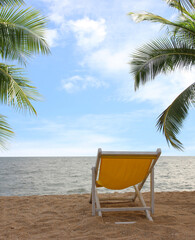Fototapeta na wymiar Beach chair on the white sand beach and coconut palm tree with cloudy blue sky