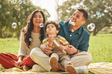 Blowing bubbles, family portrait and happy at park, bonding and having fun together outdoor. Soap...