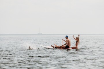 Family sea sup. Young happy father with his son and daughter Floating on a SUP board, paddling in blue sea water. summer vacation and Dad and Son Daughter concept.