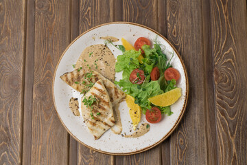 Fried fish steak with potatoes and vegetables on table
