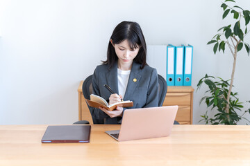 手帳に書き込む女性弁護士