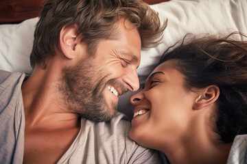Beautiful loving interracial couple laughing and kissing in bed