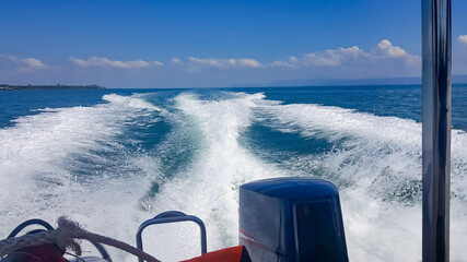 Water splash behind the ship or wake of speed boat in the ocean with beautiful blue sky and white clouds use for holiday and transportation background