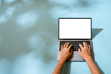 日差しと青い背景とタイピングするラップトプコンピューター