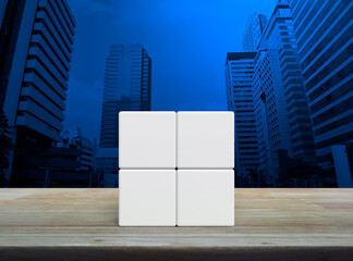 Four white block cubes on wooden table over modern office city tower and skyscraper