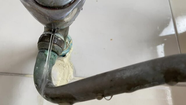 Water leaking from pipe on white wall at home kitchen sink close up view daytime. Home appliance repair and fix concept