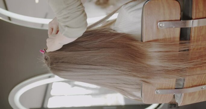 Adding hair extensions in professional salon, vertical video