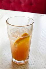 cocktail with ice and orange in a glass, on the table, in a cafe