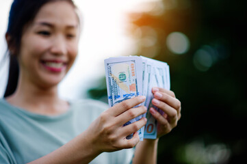 Dollar in the hands of an Asian woman Savings, Investments, Salary, Income, Cash Flow, Happiness and Financial Success and Investments.