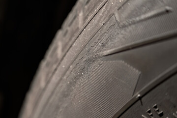 Fissures on the black rubber tire. Cracked wheel tire safety risks. Automotive service and maintenance. Worn tires macro.