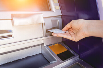 Young woman using the card for withdrawing the cash in the ATM