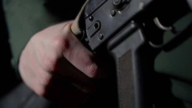 A man's hand holds a machine gun. Military weapons in the hands of a soldier. Close-up of the machine. Slow motion.