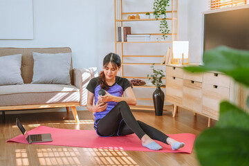 Fototapeta na wymiar Young Asian healthy woman exercising with laptop at home