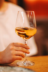 girl's hand with a glass of white wine. transparent glass with an alcoholic drink. light dry wine in a glass jar