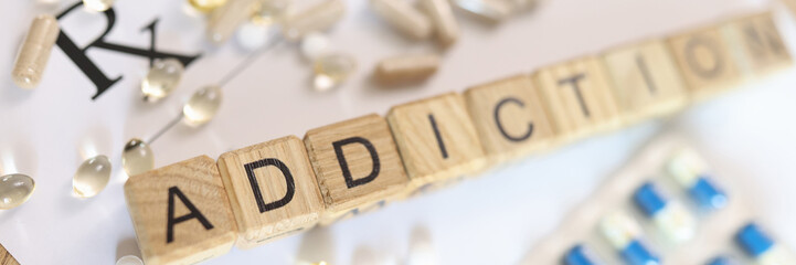 Word addiction, collected from wooden cubes with letters on doctor's prescription with many pills.