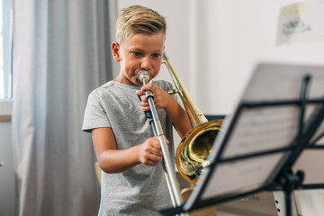 Cute Caucasian boy practicing trombone.