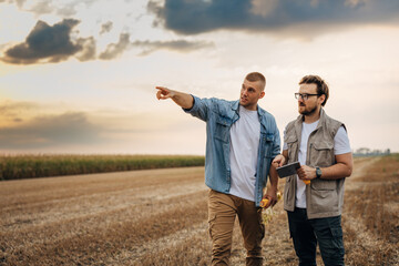 Farmer and inspector are standing in the field in countryside.