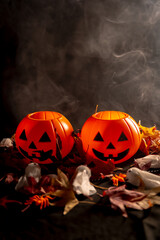 Halloween pumpkins on autumn leaves with smoke on a black background, copy paste space