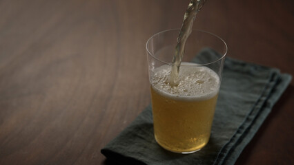 pour apple cider into tumbler glass on wood table with copy space