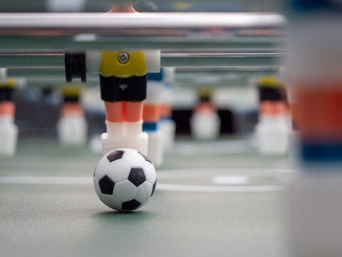 A close-up of some players and a soccer ball on a foosball table. Board game football.