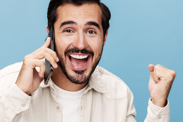 Close-up portrait of a brunette man talking on the phone, smile with teeth open mouth happiness, on a blue background in a white T-shirt and jeans, copy space