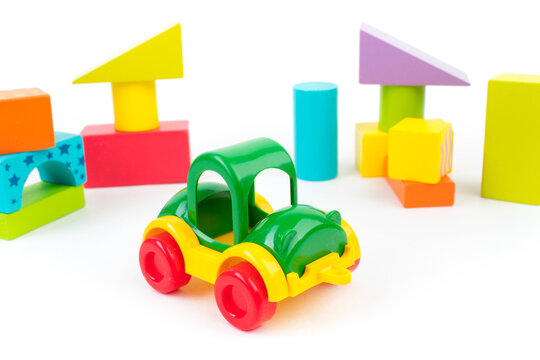 Children's toys, multi-colored car, wooden constructor cubes on a white background.