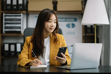 Business woman sitting at table using mobile phone, online working on laptop, searching the information on internet network.