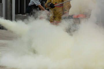 Fototapeta premium Showing how to use a fire extinguisher on a training fire for employees industry.Firefighter working on the fire site.Fire fighter concept.