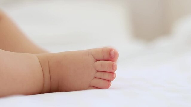 baby's small feet on a white bed, a place for text, a close-up of a little baby's feet