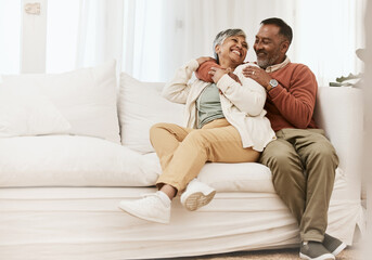 Happy, laugh and senior couple hug on sofa with conversation, care and romance in their home. Smile, embrace and elderly man with woman in living room relax, talking and enjoying retirement in house