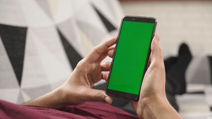Person holding a mobile phone with a green screen, ready to replace it with any content