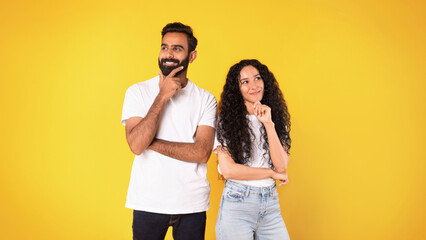 Pensive positive middle eastern couple thinking on yellow background