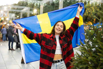 Young woman waving the Swedish flag at the New Year street fair
