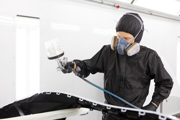 Paint shop at the car service station. The master of the paint shop paints the car. Painting a car in a paint booth