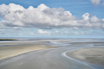 Landscape of a coast with the sea in the background and white sand covered by a little water...