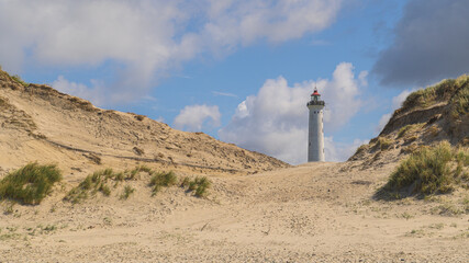 Ein Leuchtturm in den Dünen am Meer mit Sandstrand